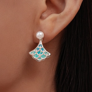 Detailed macro view of fan-shaped silver earring with pearls and opal inlay on ear