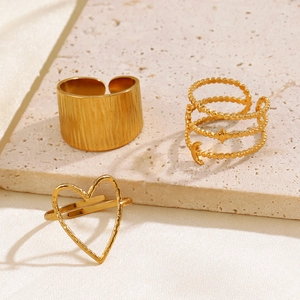 Detailed view of three gold heart and celestial rings on elegant textured stone