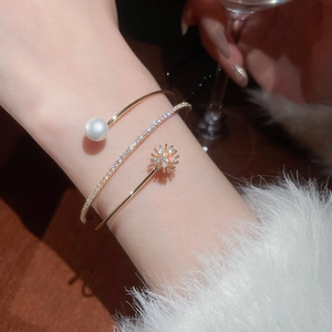 Detail of a gold layered bracelet with a white pearl and a sparkling zircon star charm