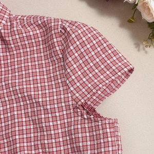Close-up of red and white gingham shirt sleeve with detailed tailoring and fabric texture