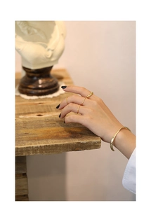 Detail view of gold irregular textured rings and a quilted open bangle on female hand