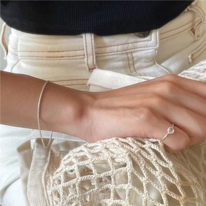 Macro detail of 925 sterling silver ring with a round crystal and fine link bracelet