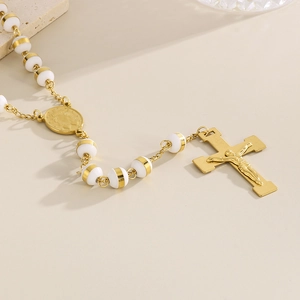 Vue détaillée du pendentif croix plaqué or 18 carats et perles blanches sur collier chapelet