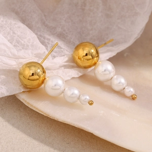 Macro shot of 18K gold-plated earrings with triple gradient pearls on a shell