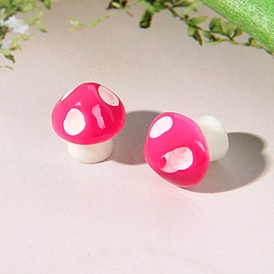 Close-up of pink and white resin mushroom stud earrings with glossy finish and clear details