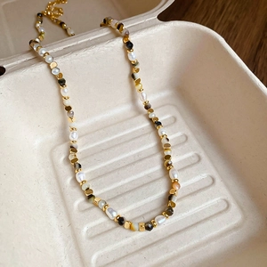 Detail of freshwater pearls, agate beads and golden metal cylinders on a beaded necklace