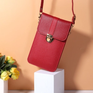 Detail of red synthetic leather mini phone bag with golden twist lock and textured finish