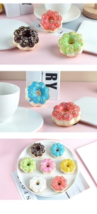 Macro shot of colorful faux donuts with sprinkles on a pastel pink background