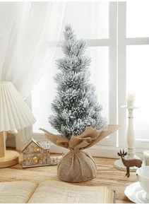 Mini frosted desktop Christmas tree with snowy flocking and a rustic burlap base detail