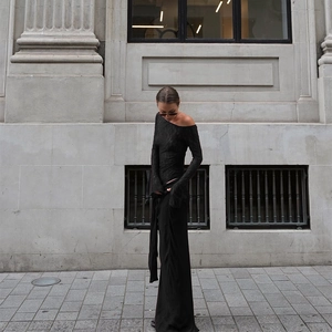 Photo de rue d'une femme en haut à épaules dénudées et pantalon large noir