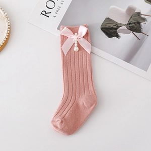 Detail of pink ribbed knit socks featuring a satin bow and delicate faux pearl charms