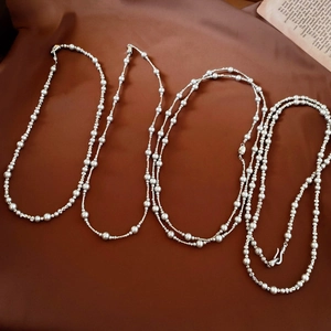 Macro view of French pearl and silver bead necklace on elegant dark silk background