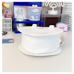 Détail de la texture crocodile blanche et du logo doré sur ce sac cylindrique rigide