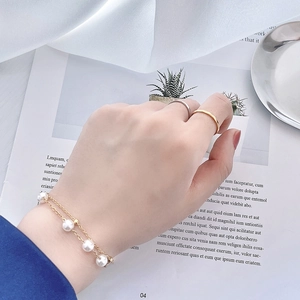 Vue détaillée d'un bracelet doré double couche avec perles porté au poignet élégant
