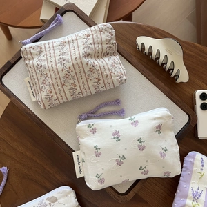 Detail of floral cotton pouches with zipper in a wooden tray on a rustic desk
