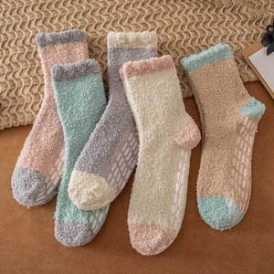 Close-up of five pairs of warm coral fleece socks with non-slip silicone grippers on soles