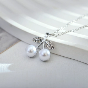 Macro shot of silver cherry pendant with sparkling crystal leaves and white pearls