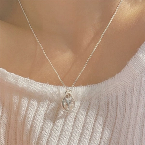 Close-up of minimalist sterling silver triple interlocking ring necklace on a white sweater
