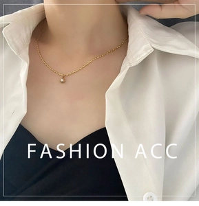 Close-up of golden titanium steel necklace with a white pearl pendant on a fashion model