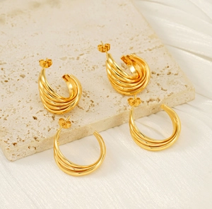 Macro view of multi-layered 18K gold-plated irregular loop earrings on white silk