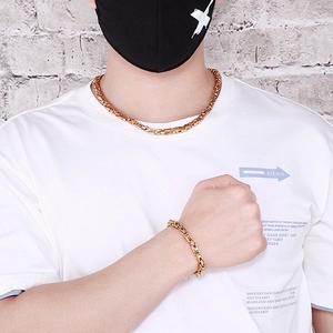 Dettaglio del set collana e bracciale bizantino dorato da uomo indossato da un modello