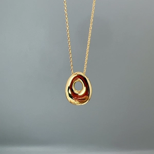 Close-up of golden teardrop hollow pendant with polished mirror finish on thin chain
