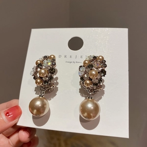 Detail of floral earrings with sparkling rhinestones and champagne imitation pearls