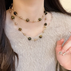 Detail der Tigerauge-Perlenkette mit goldenen Akzenten am Hals des Models