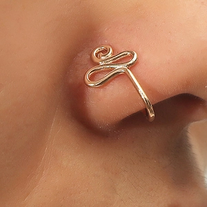 Macro shot of gold spiral U-shaped nose ring clip on woman's nose wing detail