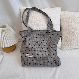 Detail of polka dot canvas bag with bow embroidery and branded label in a cozy home setting