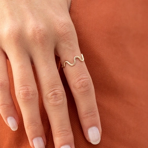 Detailed view of elegant gold-tone wavy cross ring worn on a model finger