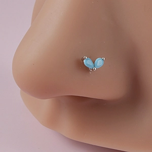 Close-up of silver nose stud with two blue teardrop gemstones on model nose