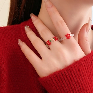Close-up of handmade beaded flower ring with red petals and clear beads on model hand