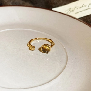 Macro shot of 18k gold plated open ring with round tiger eye stone and textured metal detail