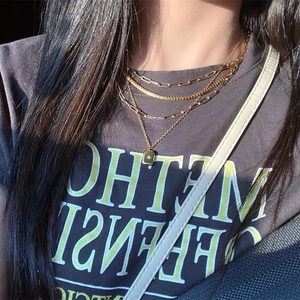 Detail of layered gold necklaces with paperclip chain, snake chain and star pendant