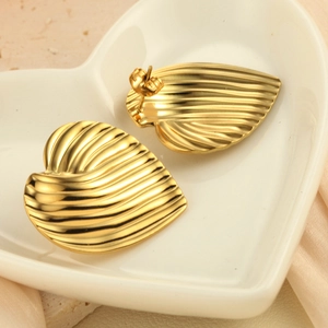 Boucles d'oreilles cœur dorées minimalistes avec finition texturée sur plat céramique