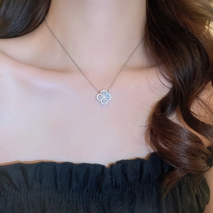 Macro shot of silver clover necklace with clear cubic zirconia on female model