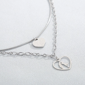 Macro detail of silver double-layer necklace with kissing couple silhouette heart pendant