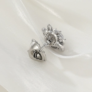 Detailed view of silver bow brooch with crystal droplets on white silk fabric