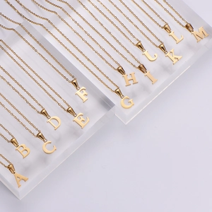 Polished 18k gold plated stainless steel initial necklaces on clear acrylic display