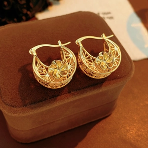 Macro shot of gold hollow flower earrings with intricate geometric patterns and matte finish