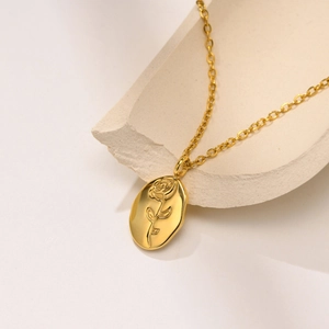Detailed macro view of a golden oval pendant with a rose flower embossing on a stone