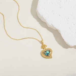 Detail of a gold heart necklace with abalone shell inlay on white stones