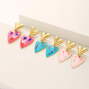 Detail of colorful enamel heart earrings in pink and blue on geometric stands