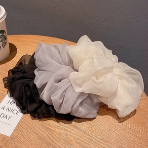 Close-up of black, grey and white chiffon oversized hair scrunchies on a wooden table