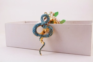 Detail of a gold snake keychain with blue crystal rhinestones on a white box