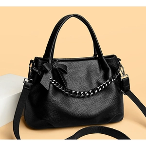 Detail of black soft leather tote with chic chain accent and decorative bow charm