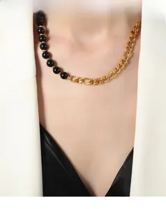 Detail of stone bead and gold chain necklace worn with an elegant white blazer