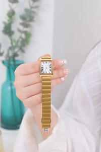 Detail of a vintage rectangular quartz watch with gold metal strap and Roman numeral dial