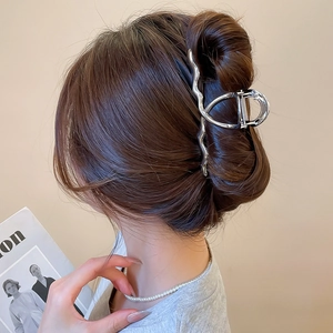 Close-up of a silver wavy metal hair claw clip styled on a model's brown hair